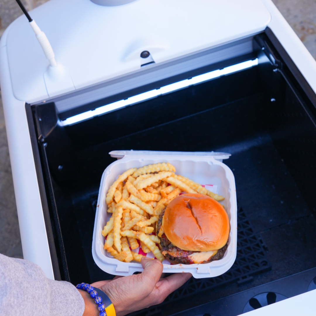 A student grabs a meal from a delivery robot. 